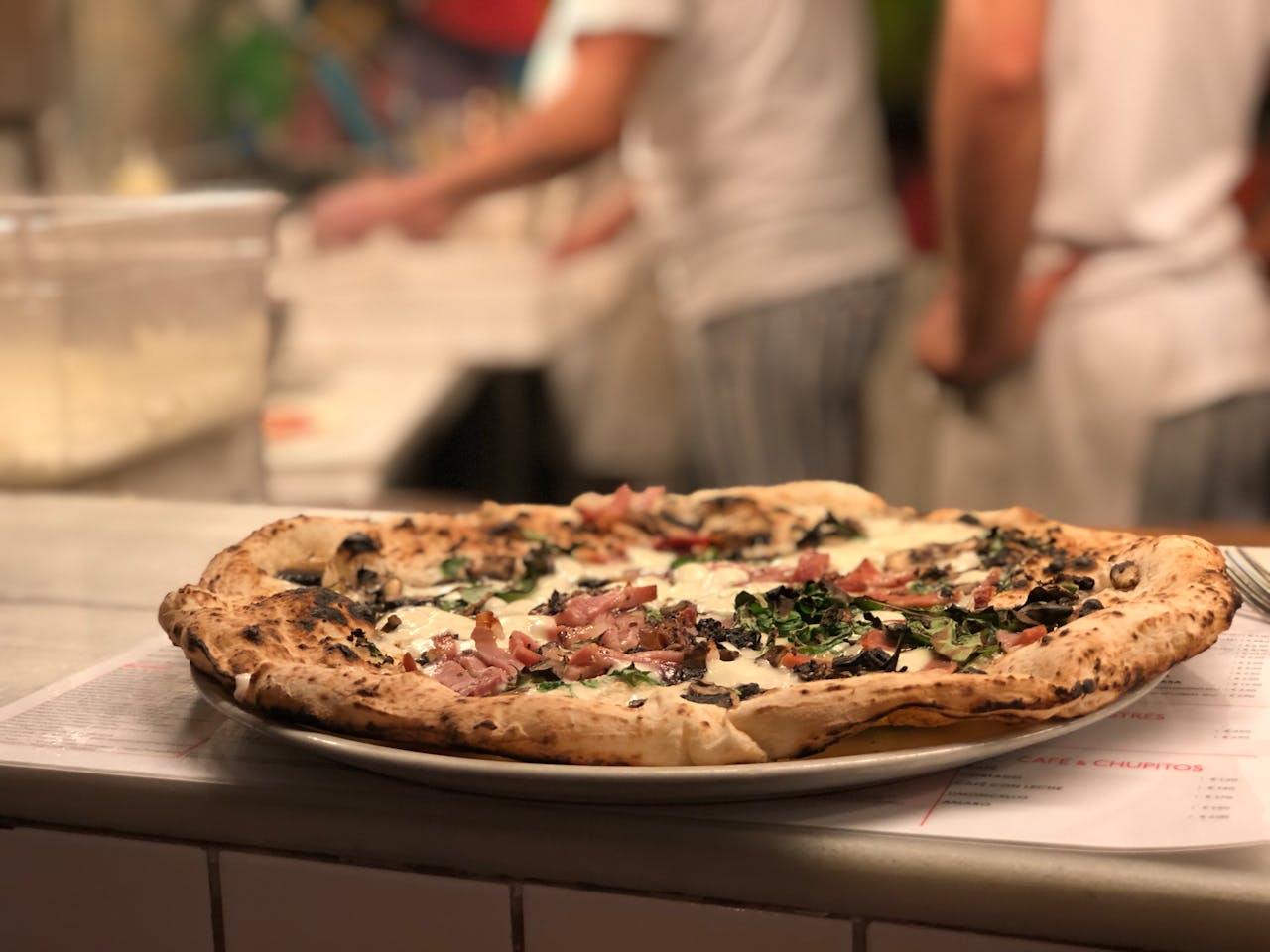 Mouth-watering Italian pizza with meat and herbs in a cozy indoor pizzeria setting.